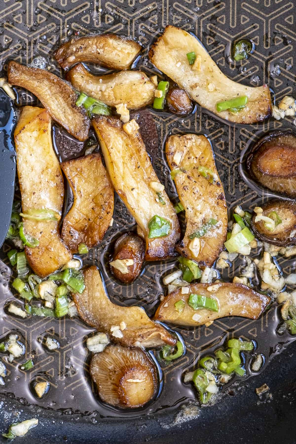 Pan-fried king oyster mushrooms garnished with green onions.