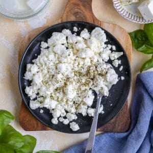 Crumbled feta cheese seasoned with oregano on a white plate.