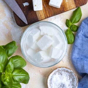 Feta cheese stored in brine in a jar, kosher salt on the side.