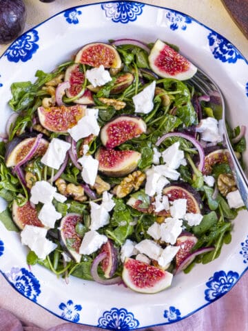 Arugula and fig salad in a white salad bowl.