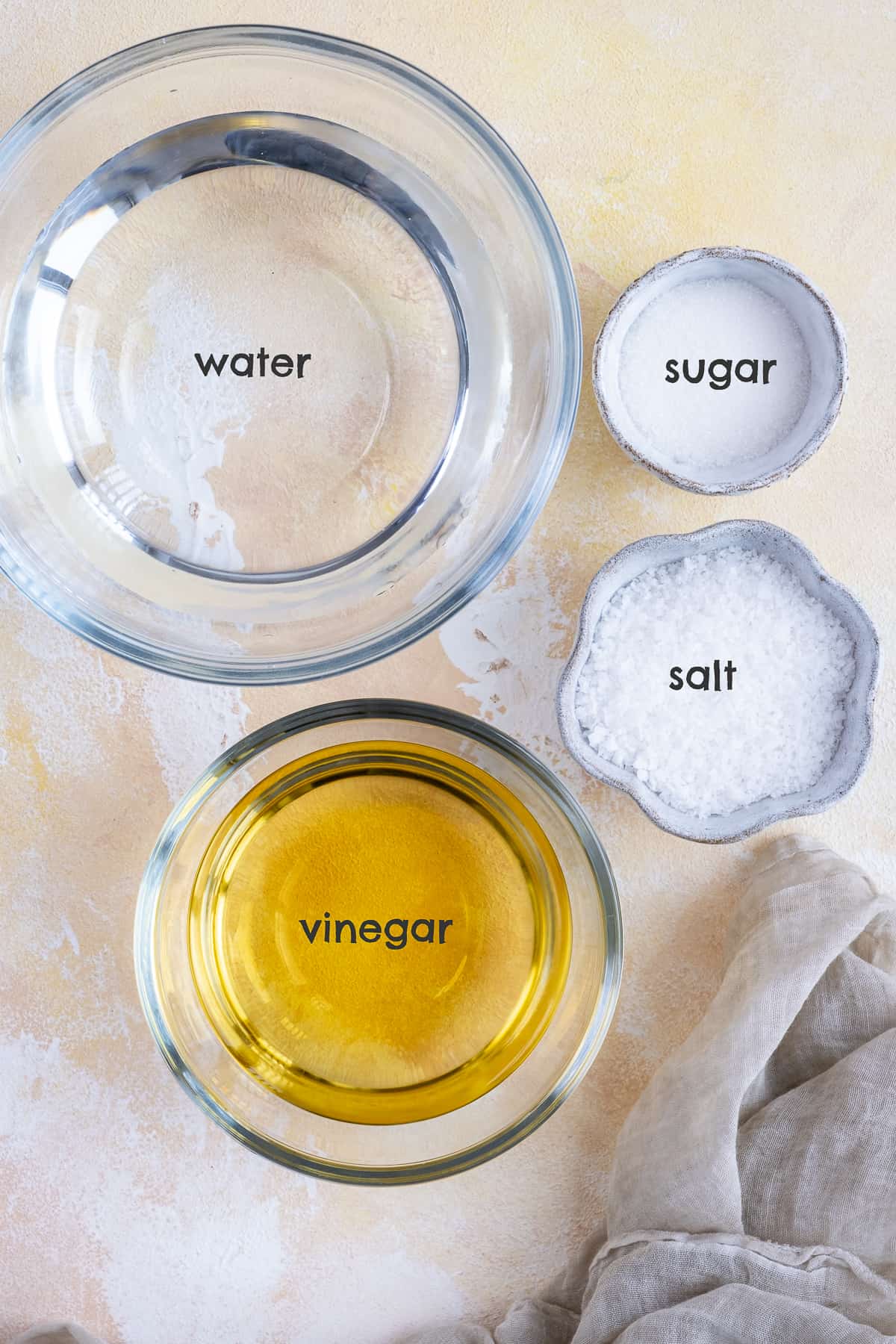 Vinegar, water, salt and sugar in bowls.
