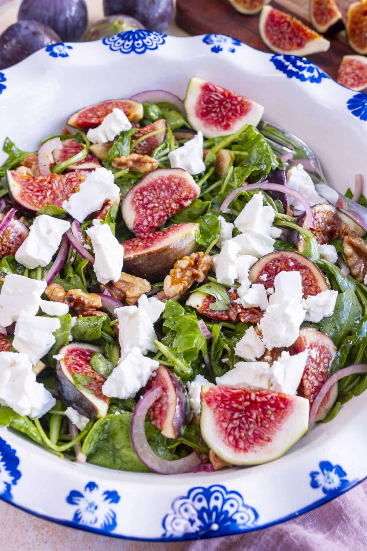Fig salad with arugula in a white bowl close shot.