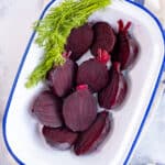 Halved boiled beets with fresh dill in a serving dish.