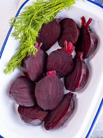 Halved boiled beets with fresh dill in a serving dish.