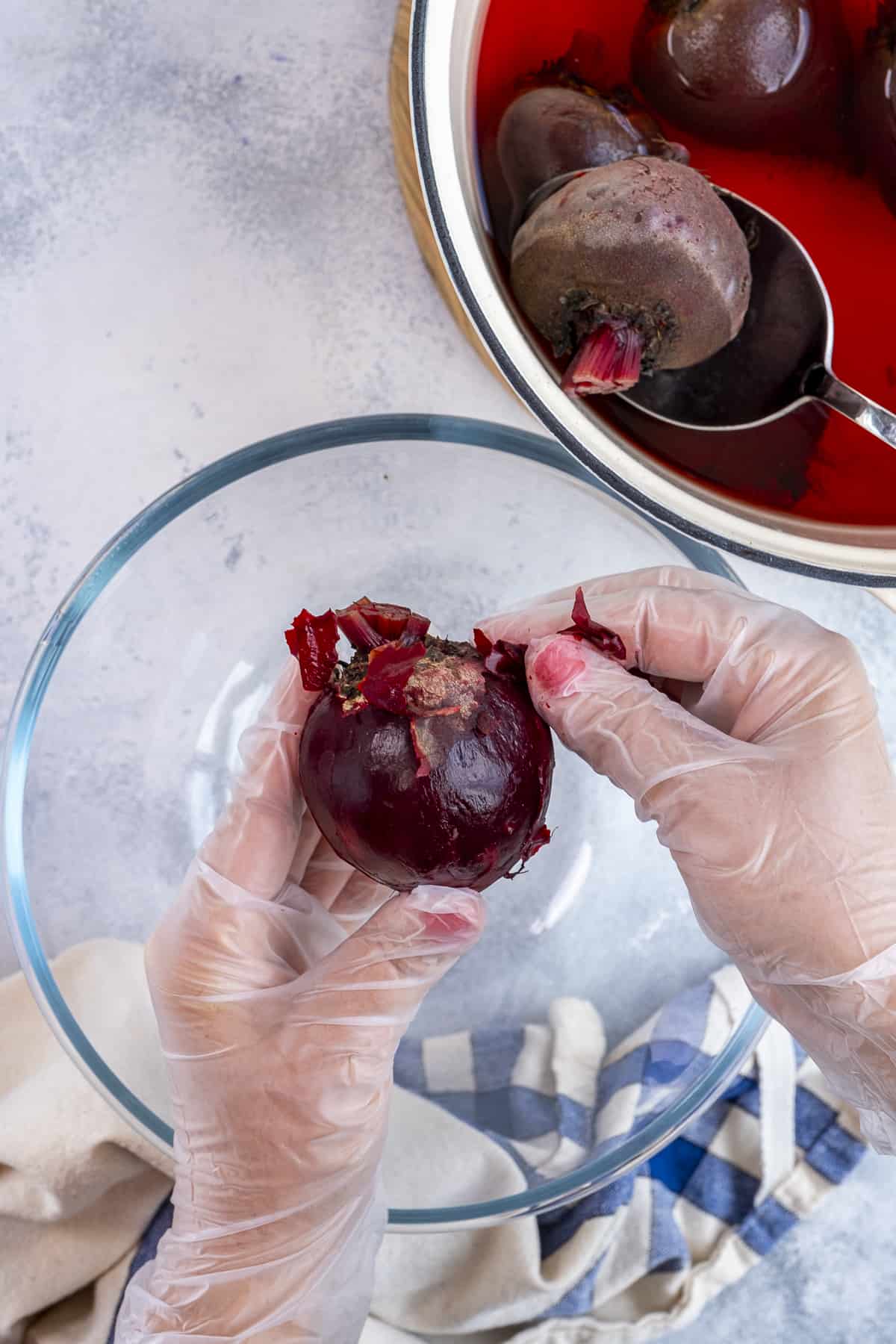 Hands removing the skin of cooked beets.