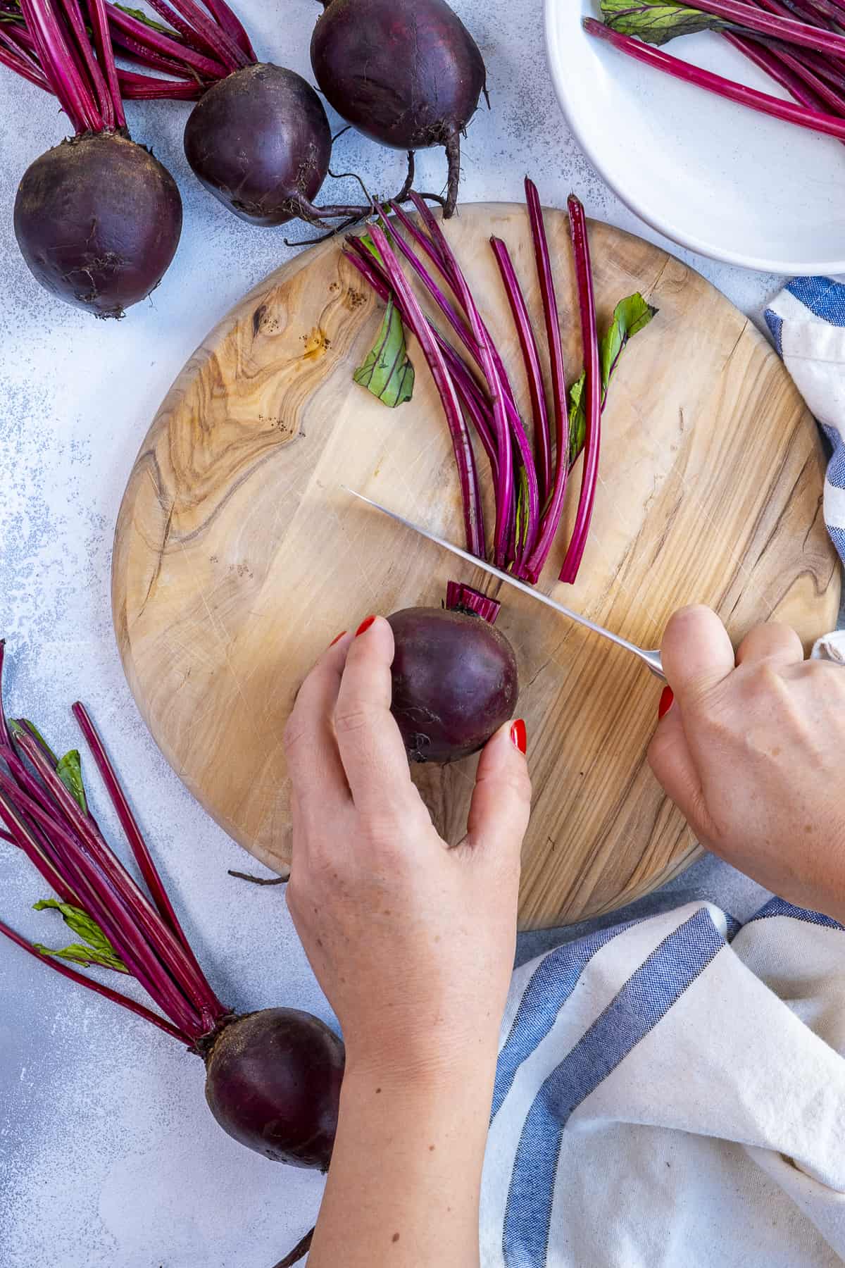 Hands cutting off the stems of beets.