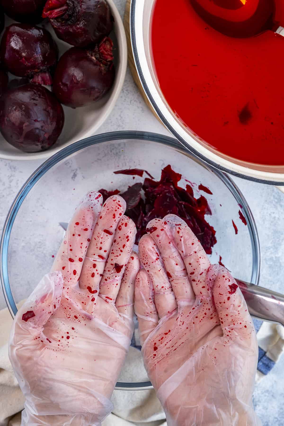 Hands with gloves showing the stains of beets.