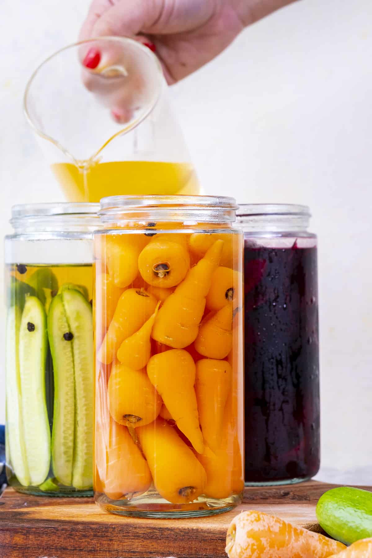 Hand pouring brine into pickle jars.