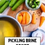 Pickling brine being poured into jars with cucumbers and carrots for homemade pickles.