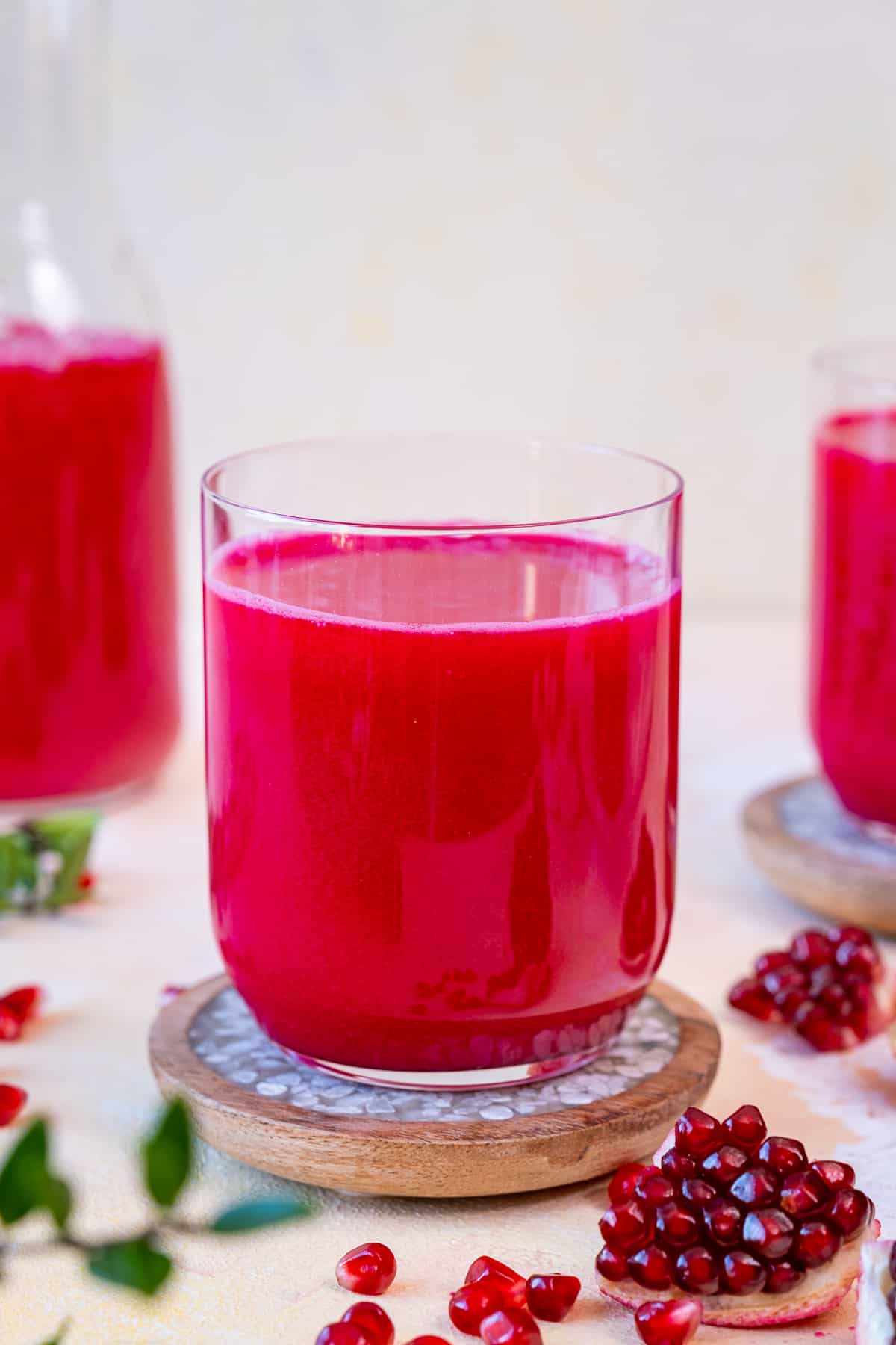 Pomegranate juice in a glass and pomegranate seeds on the ground.