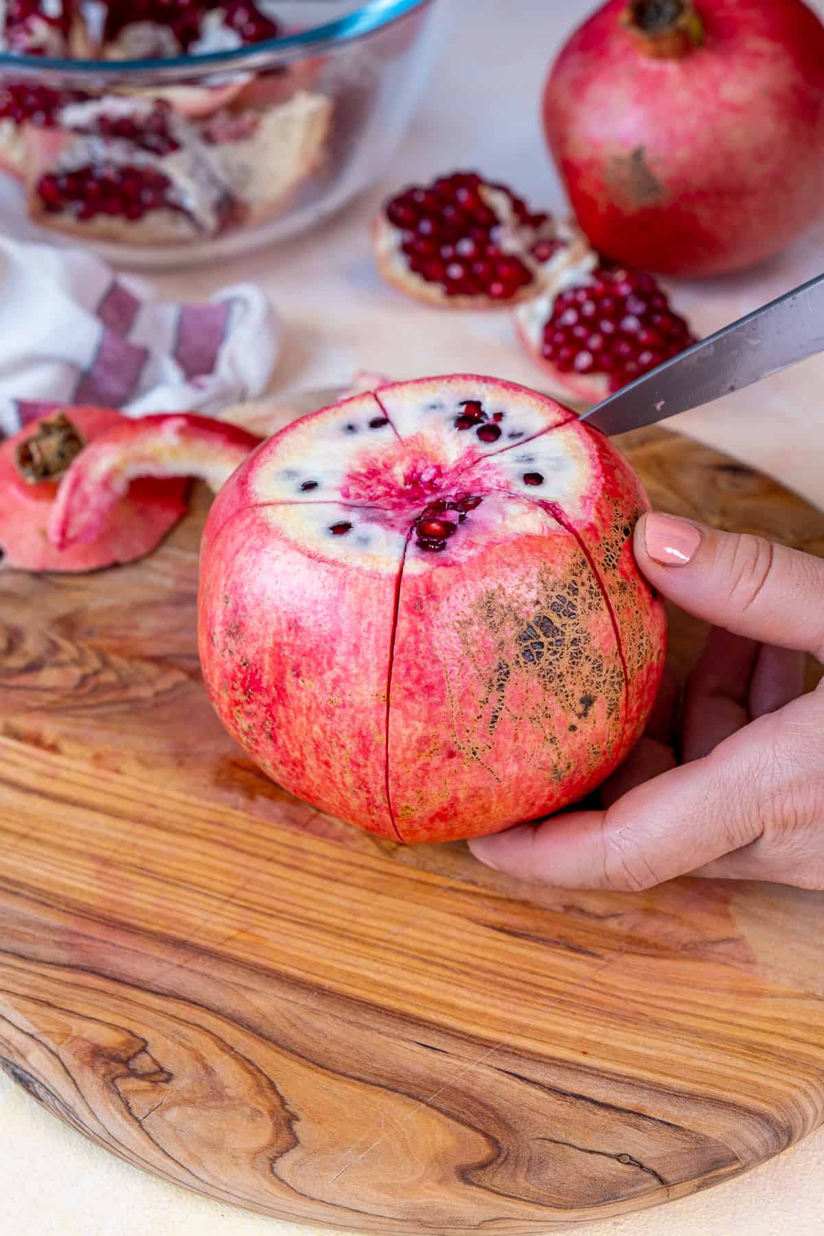Hands showing how to cut a pomegranate into segments.