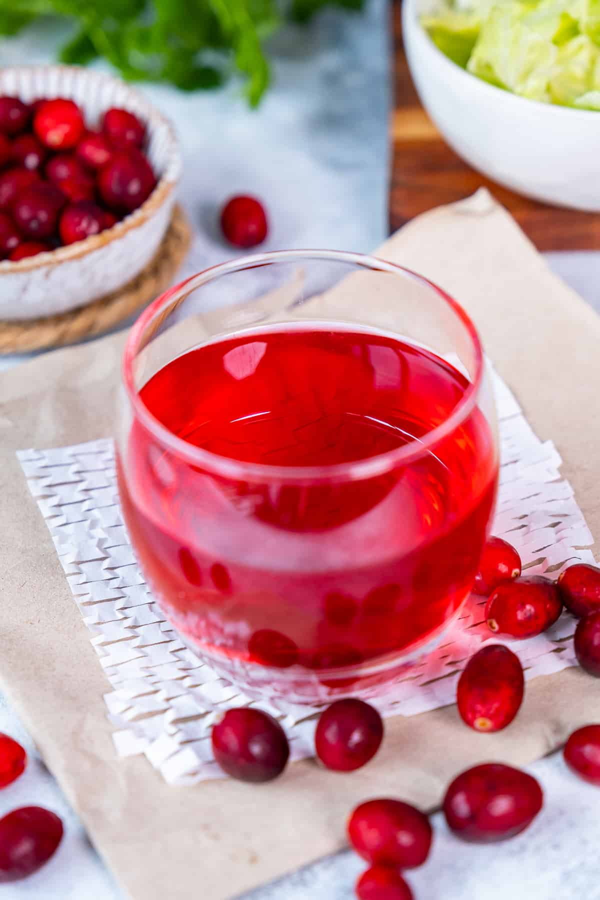 A glass of cranberry juice and fresh cranberries around it.