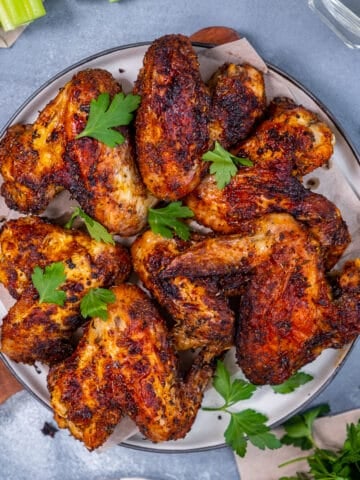 Fried whole chicken wings garnished with parsley on a plate.