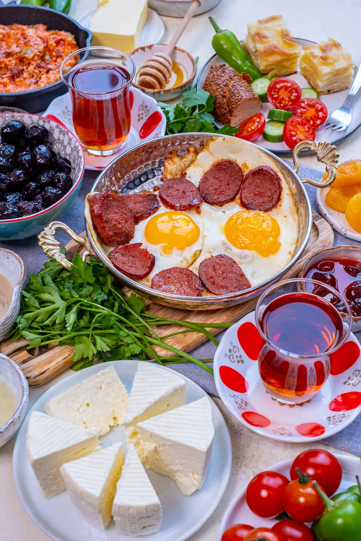 Turkish breakfast with eggs and sujuk, olives, cheese and Turkish tea in tulip glasses.