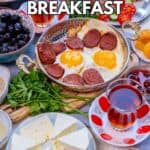 Turkish breakfast with eggs and sujuk, olives, cheese and Turkish tea in tulip glasses.