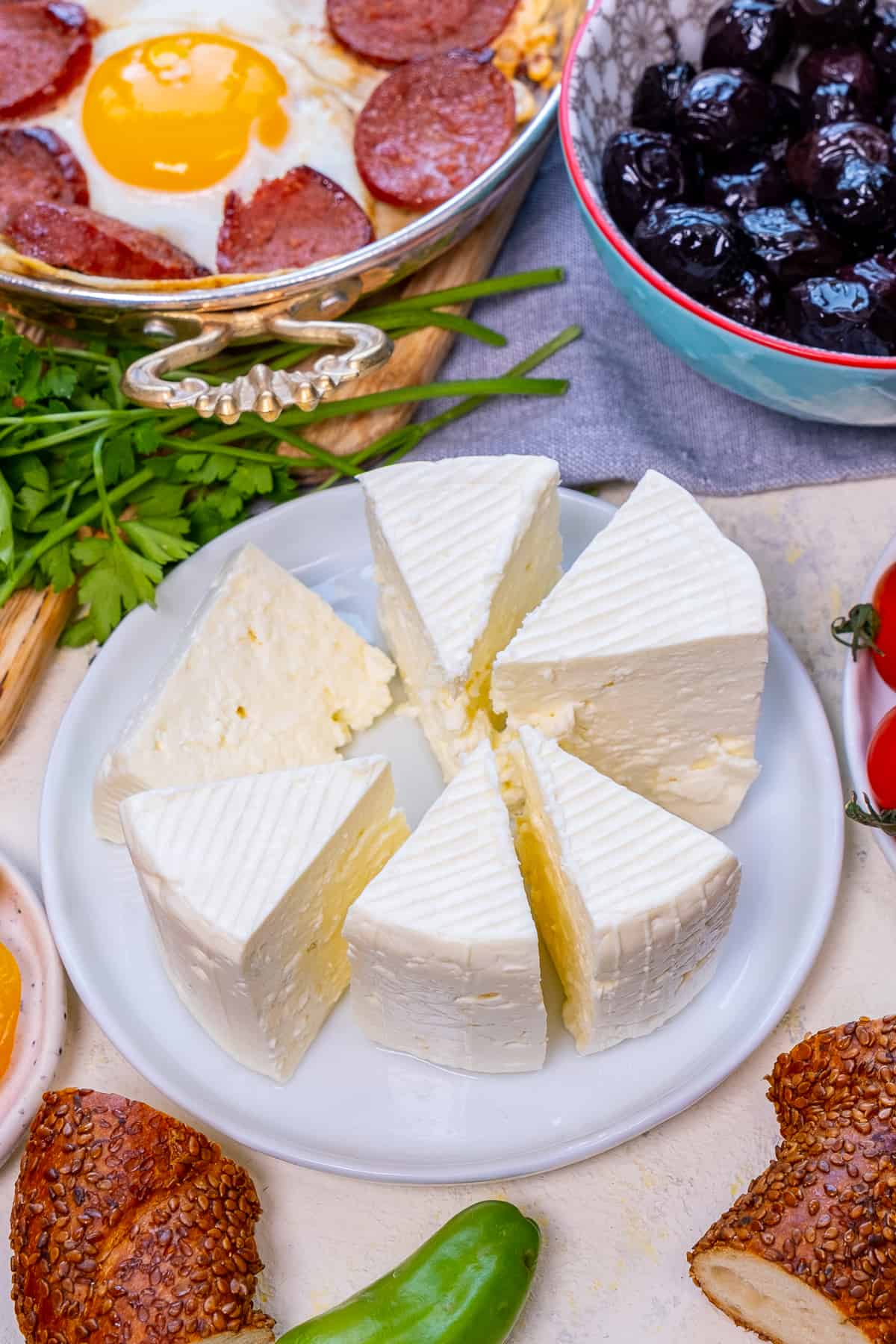 Turkish cheese sliced on a white plate, other breakfast foods around it.