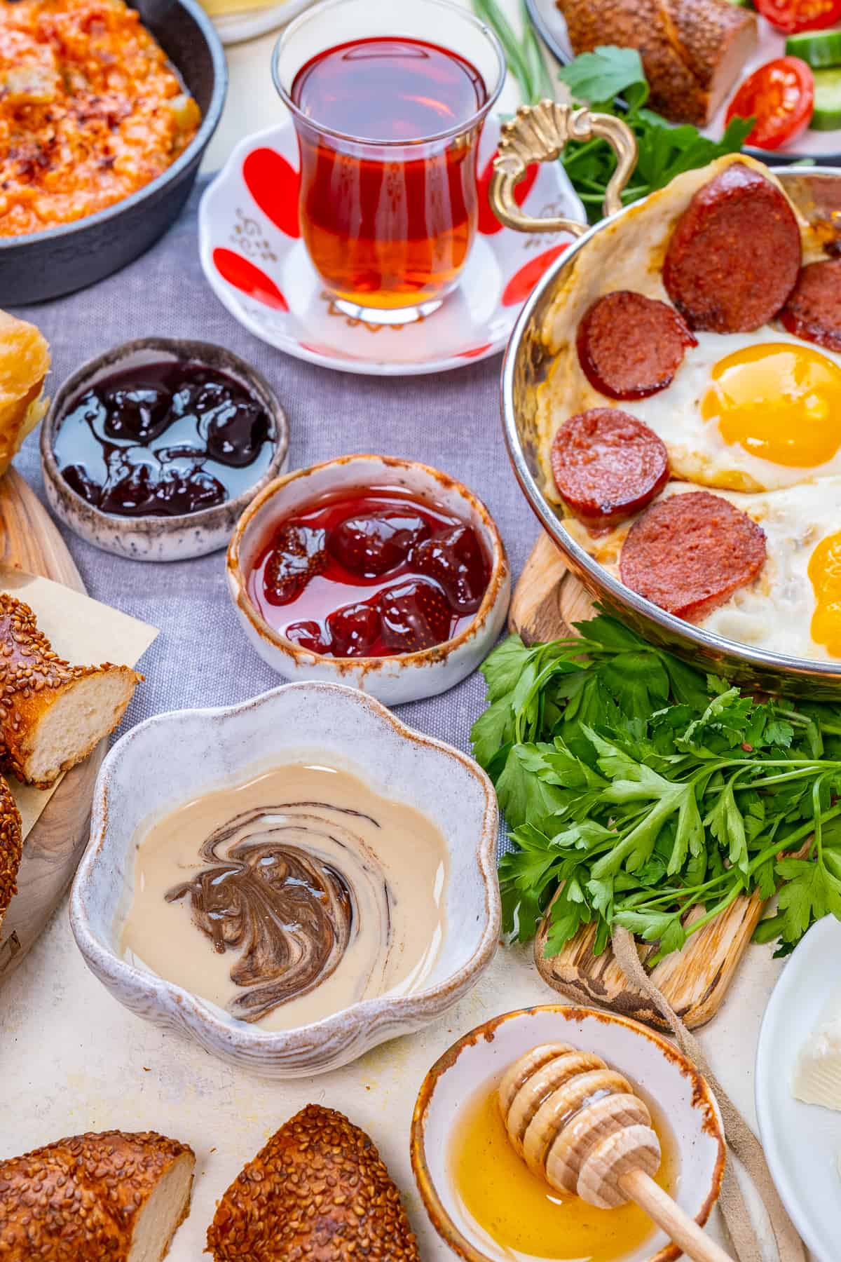 Turkish breakfast with tahini and molasses mixture, jams, honey, eggs with sucuk and Turkish tea.