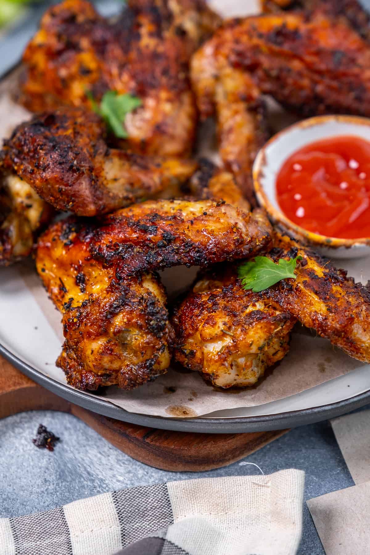 Air fried whole wings served on a plate with a hot sauce in a small bowl.