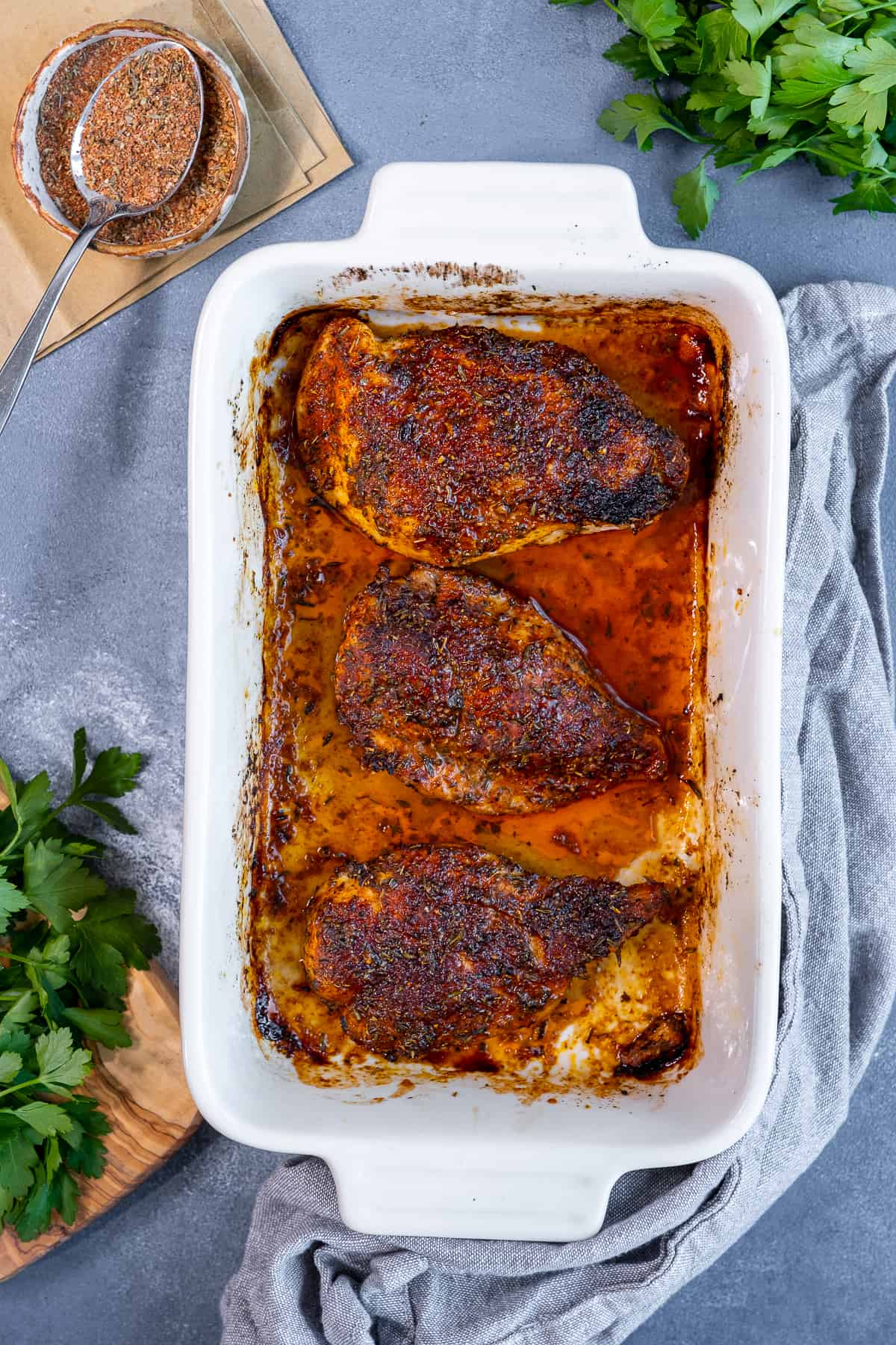 Dry rubbed chicken breasts in a baking pan.