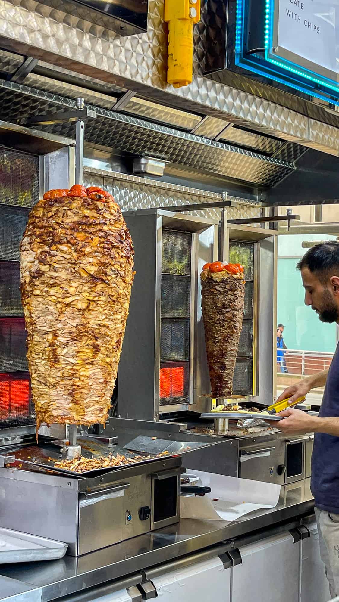 Chicken doner kebab and lamb doner kebab on vertical spits in a shop.