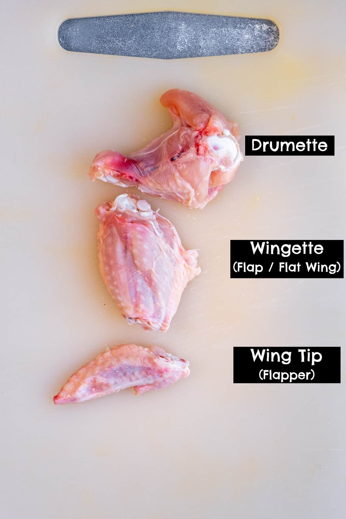 A drumette, a wignette and a wing tip on a white cutting board.