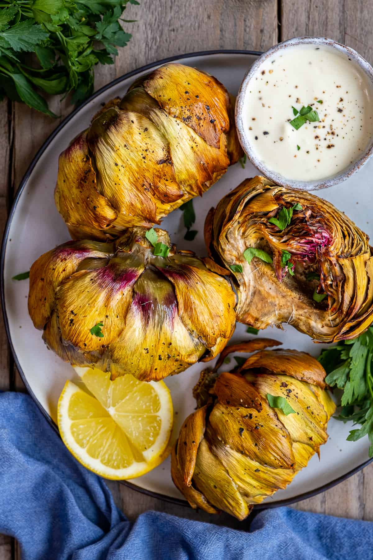Air fried artichokes served with lemon slices and a dipping sauce on the side.