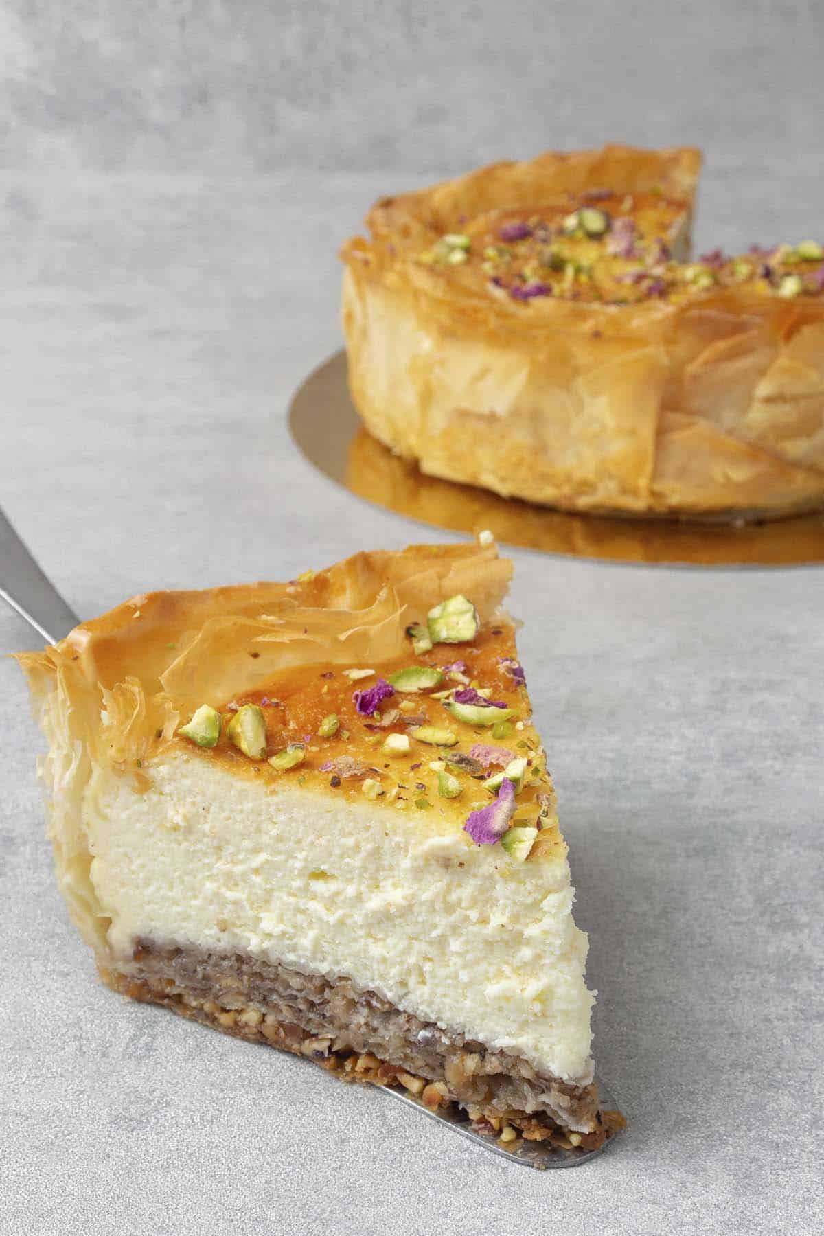 A close shot of a slice of baklava cheesecake on a serving spatula.