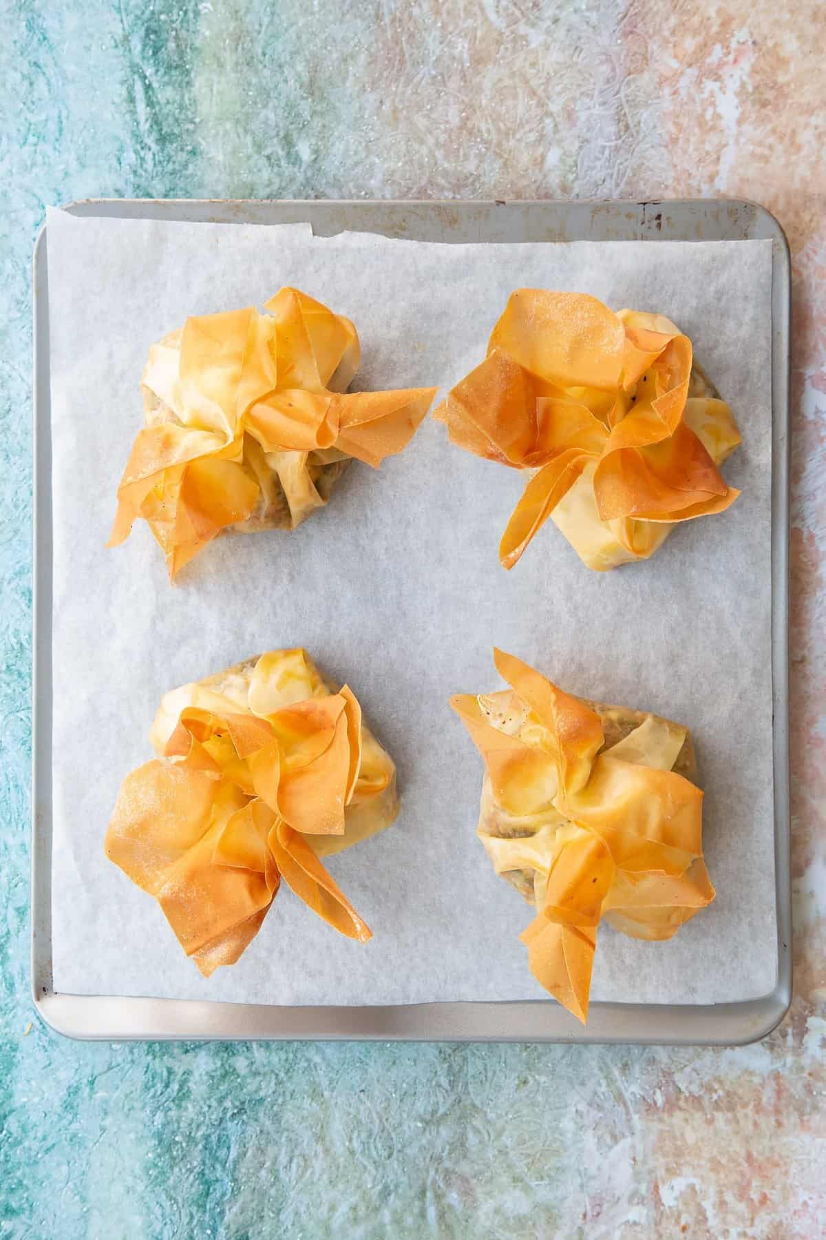 Filo parcels stuffed with goat cheese on a piece of parchment paper.