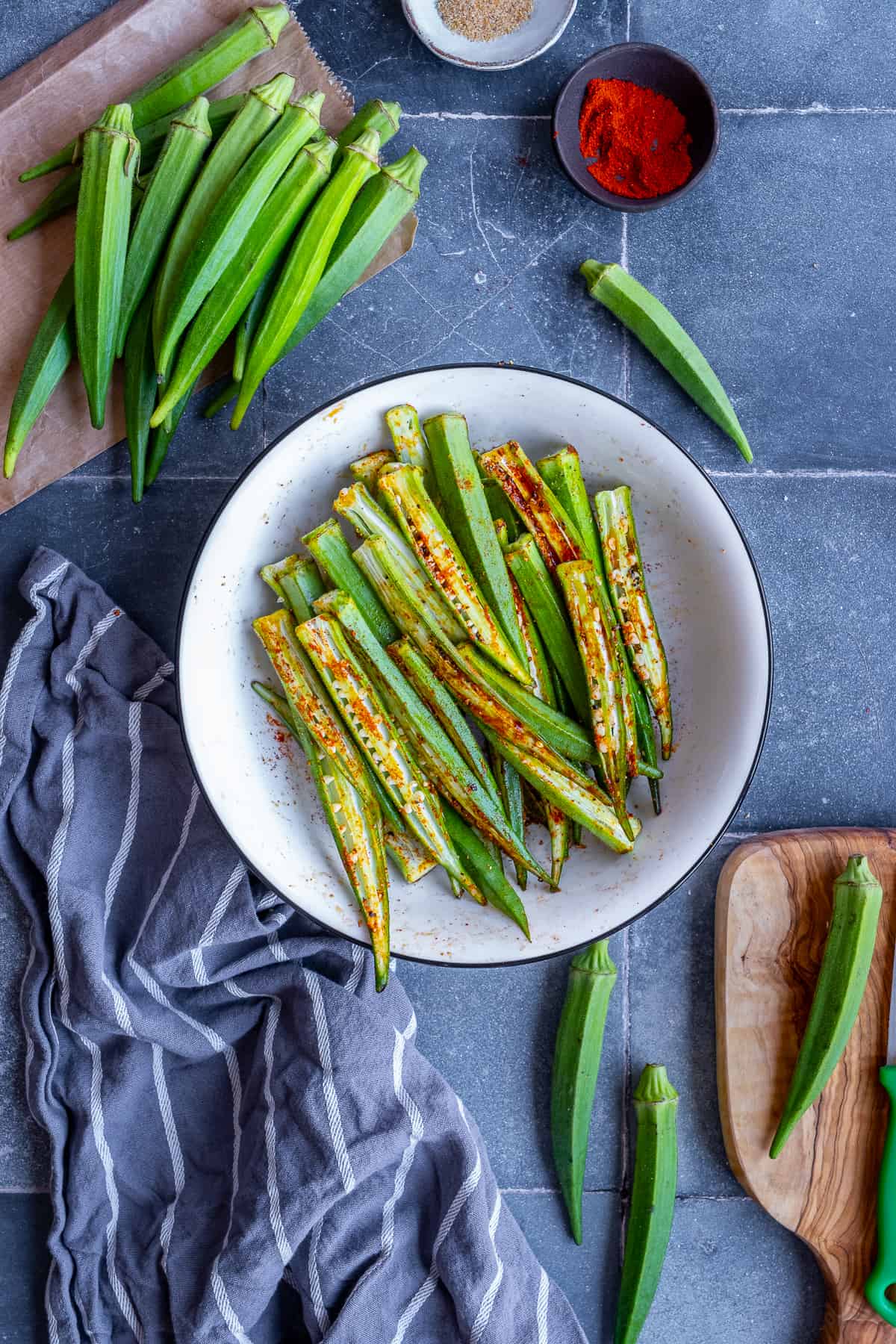 Okra sliced lengthwise in a bowl, seasoned with spices.