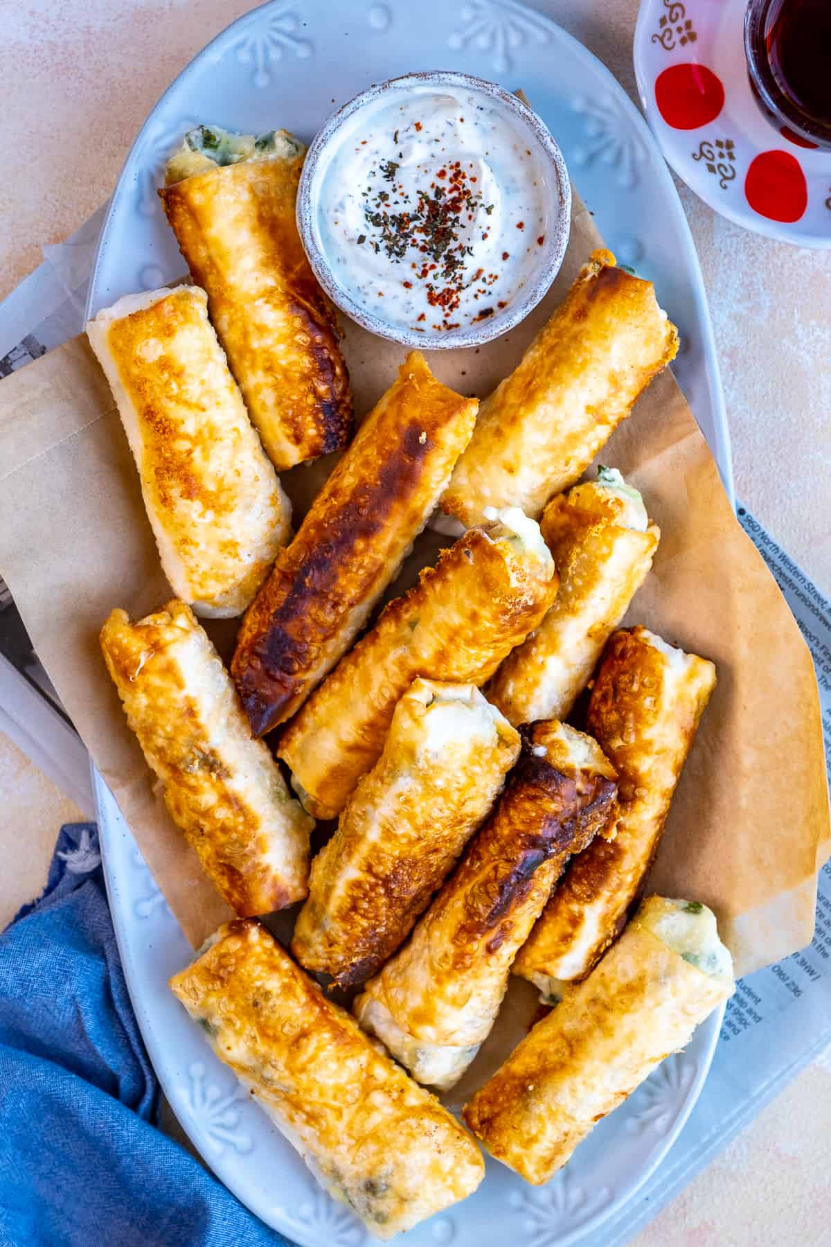 Turkish cheese rolls with filo on a white plate, yogurt sauce on the side.