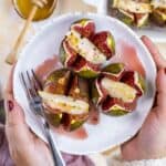 Hands holding a plate of goat cheese stuffed figs.