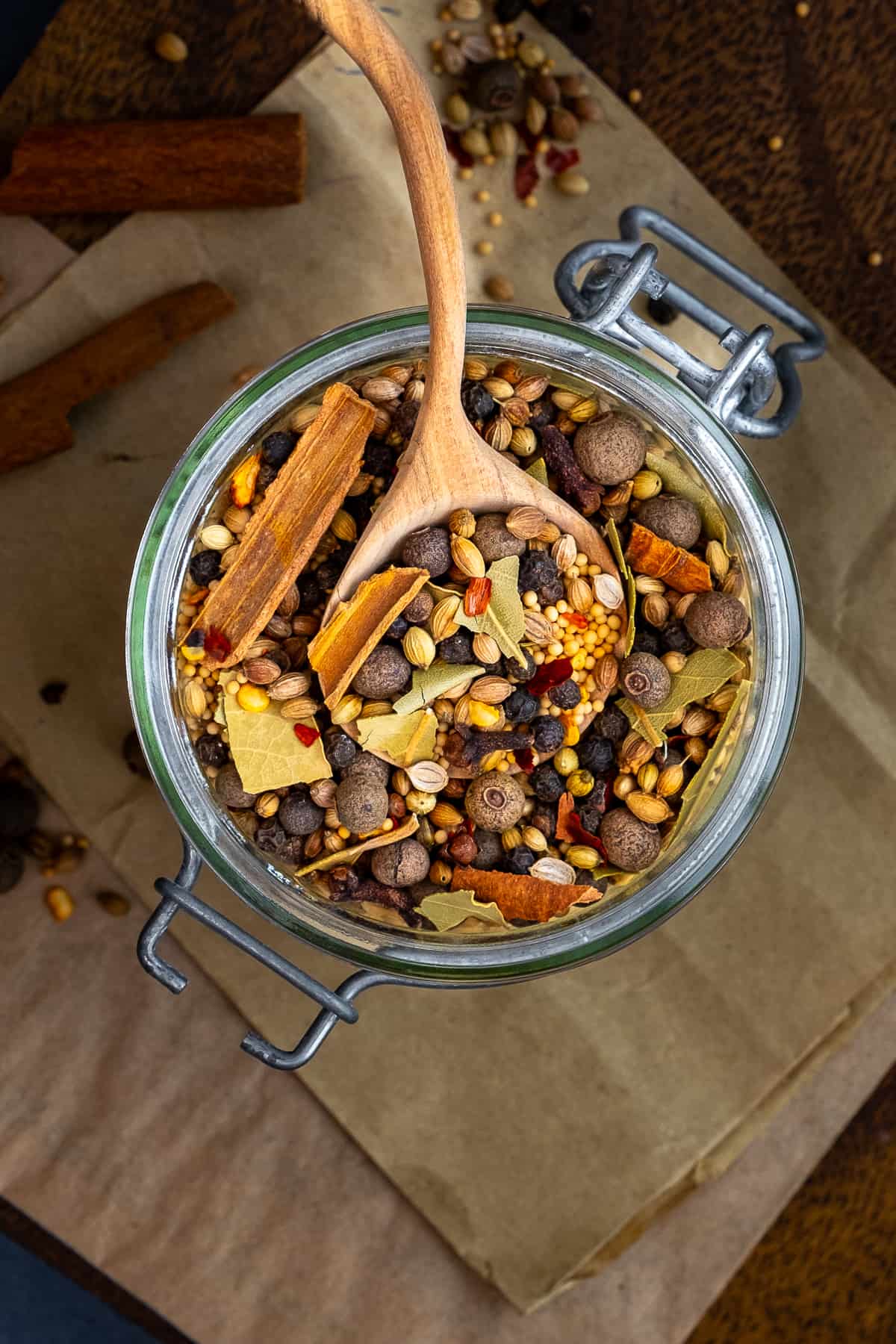 Pickling spice mix in a jar and a wooden spoon inside it.