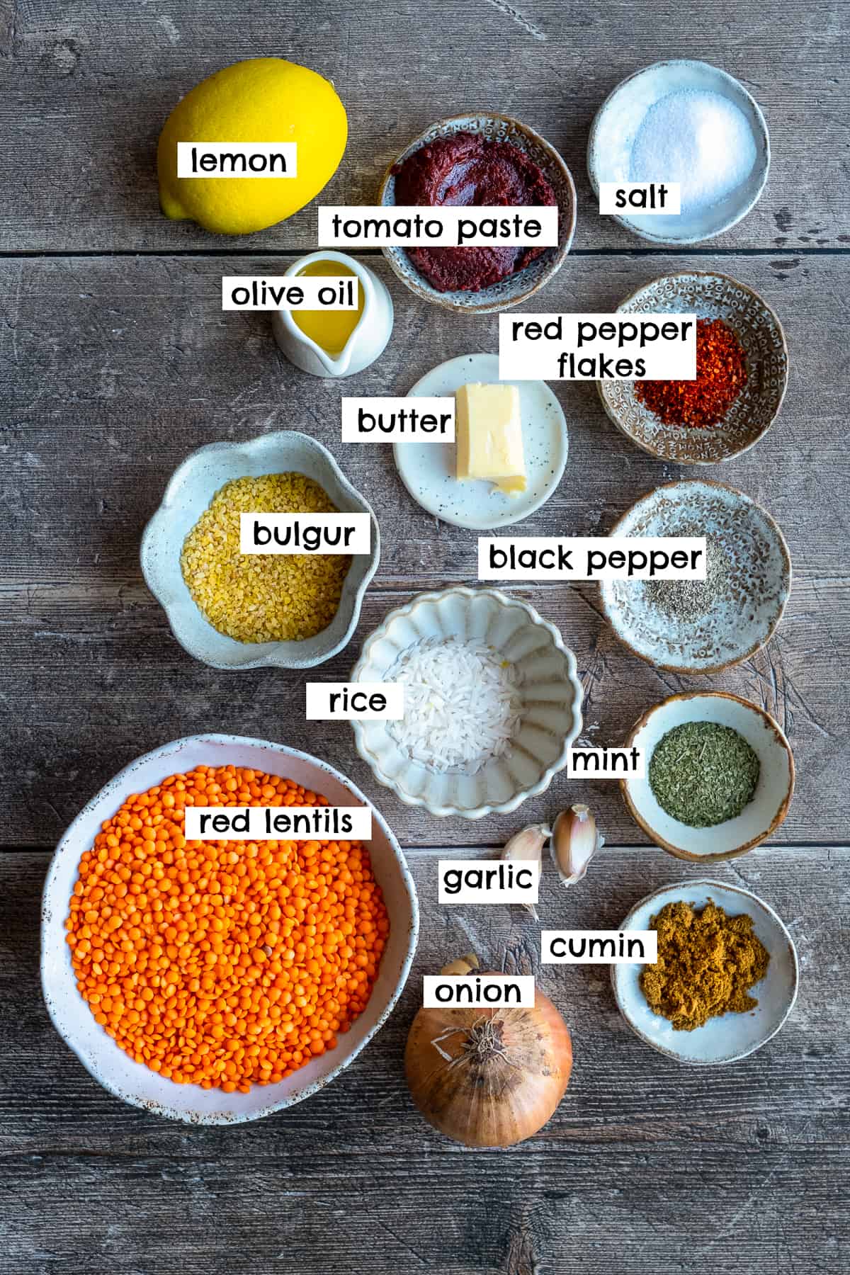 Red lentils, bulgur, rice, onion, garlic, butter, olive oil, lemon, tomato paste, salt and pepper, red pepper flakes, dried mint, cumin photographed from top view.