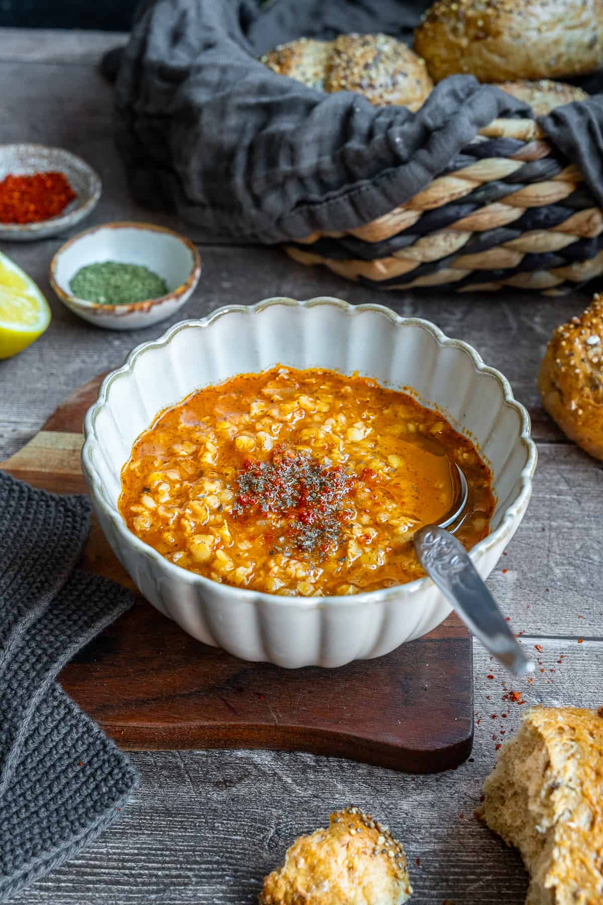 Ezogelin soup garnished with dried mint and pepper flakes in a white bowl and a spoon inside it.