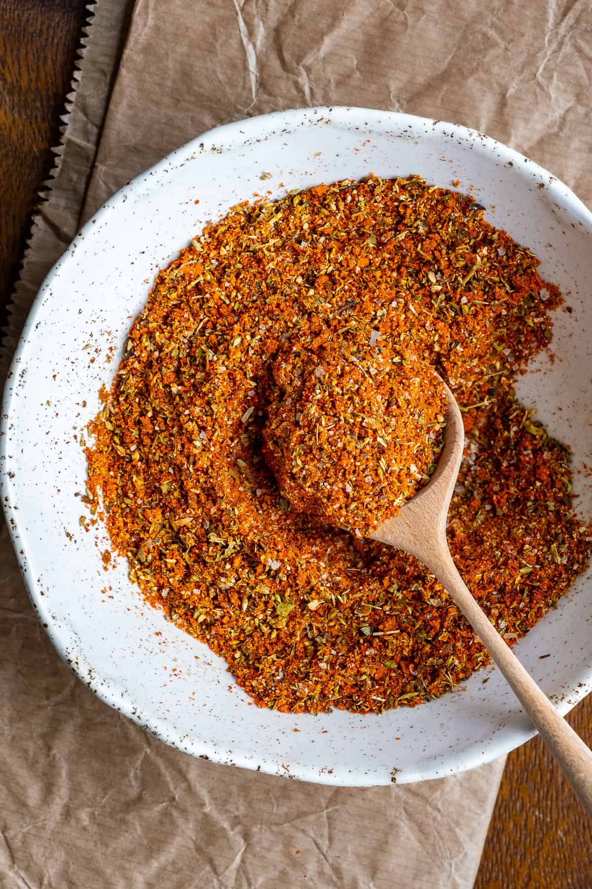 Spice mix in a white bowl and a wooden spoon inside it.