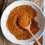 Turkish spice mix in a white bowl and a wooden spoon inside it.