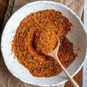 Turkish spice mix in a white bowl and a wooden spoon inside it.