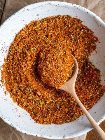 Turkish spice mix in a white bowl and a wooden spoon inside it.