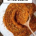 Spice mix in a white bowl and a wooden spoon inside it.