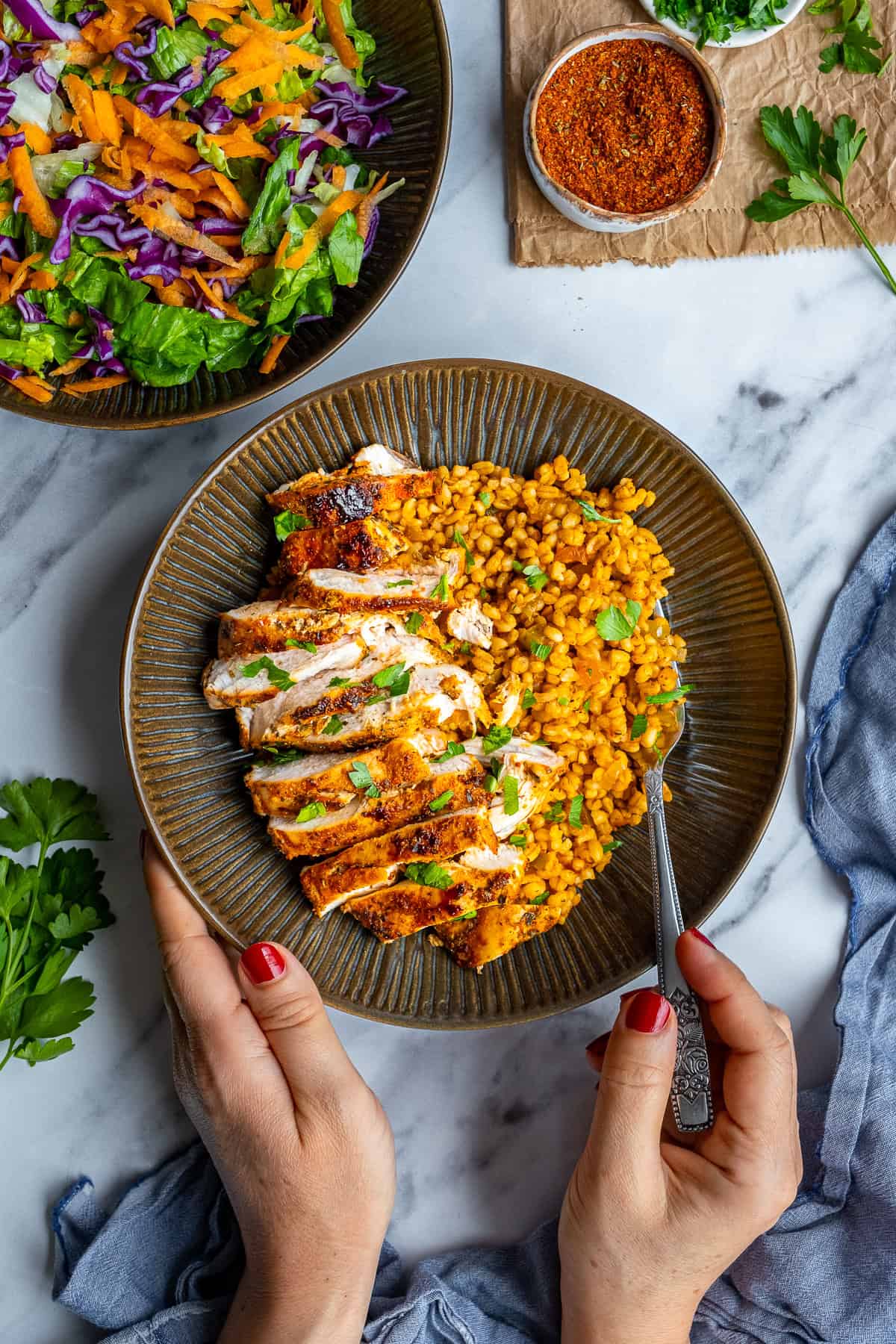 Pan-fried chicken breast sliced and served with bulgur pilaf in a bowl and a woman about to eat it.