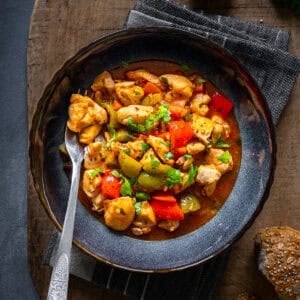 Turkish chicken dish with a tomato sauce served in a bowl and a fork inside it.