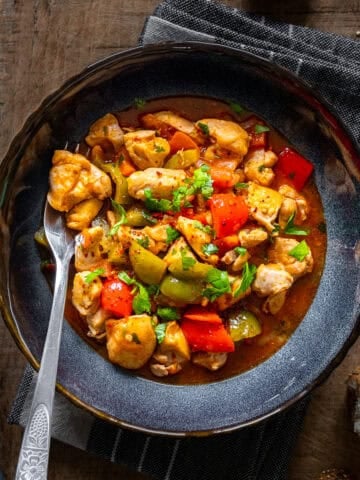 Turkish chicken dish with a tomato sauce served in a bowl and a fork inside it.