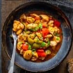 Turkish chicken dish with a tomato sauce served in a bowl and a fork inside it.
