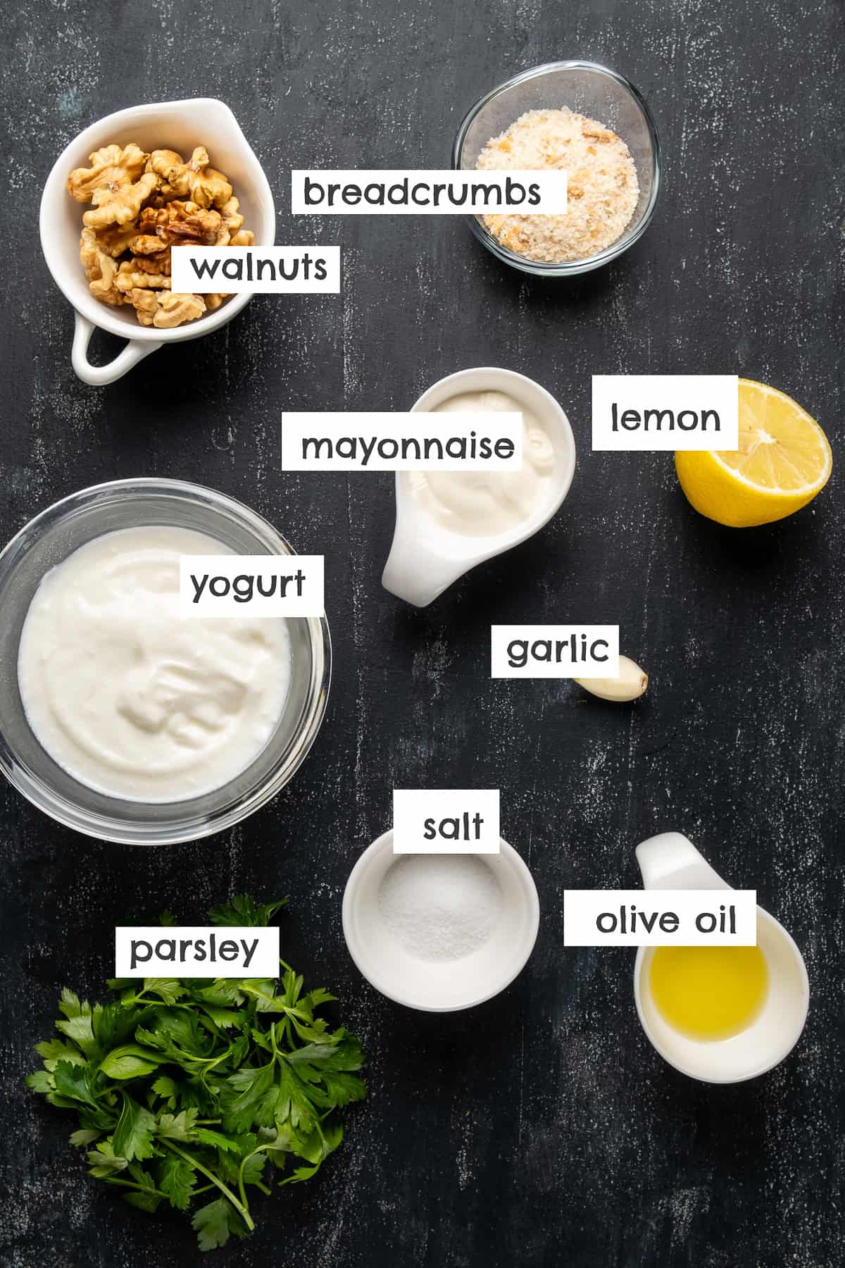 Walnuts, yogurt, breadcrumbs, lemon, olive oil, mayonnasie, salt. garlic, parsley photographed together from top view.