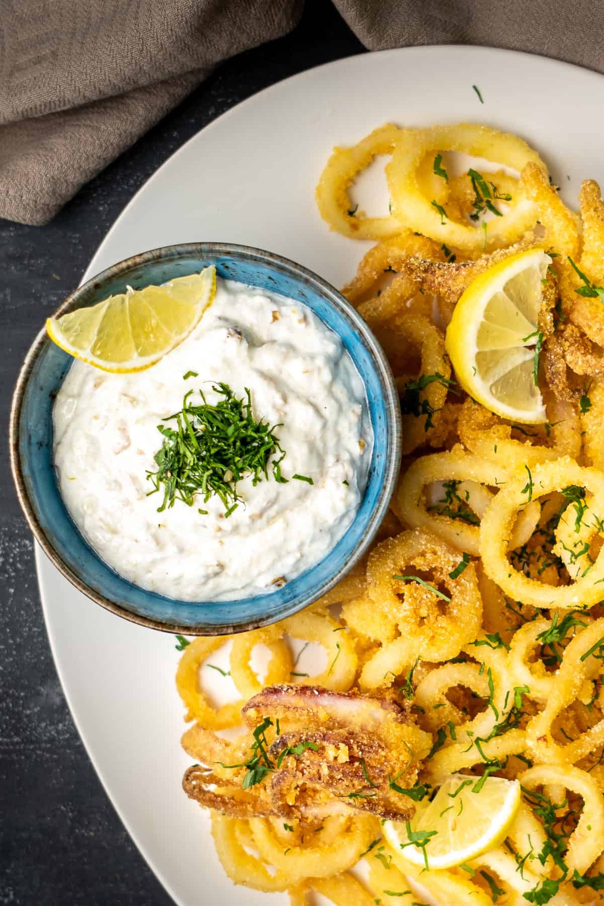 Yogurt and walnut-based tarator sauce in a bowl served as a dip on the side of fried calamari.