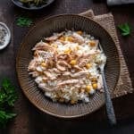 A plate of Turkish rice with shredded chicken and chickpeas (Tavuklu Pilav), served with a fork on a rustic table.