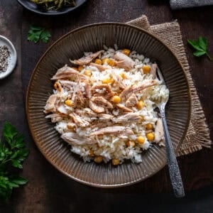 A plate of Turkish rice with shredded chicken and chickpeas (Tavuklu Pilav), served with a fork on a rustic table.