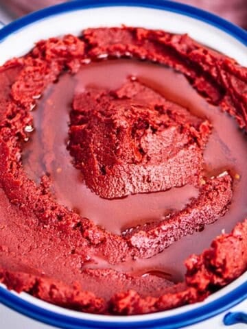 A bowl of thick, vibrant red homemade tomato paste with a swirl of olive oil on top.