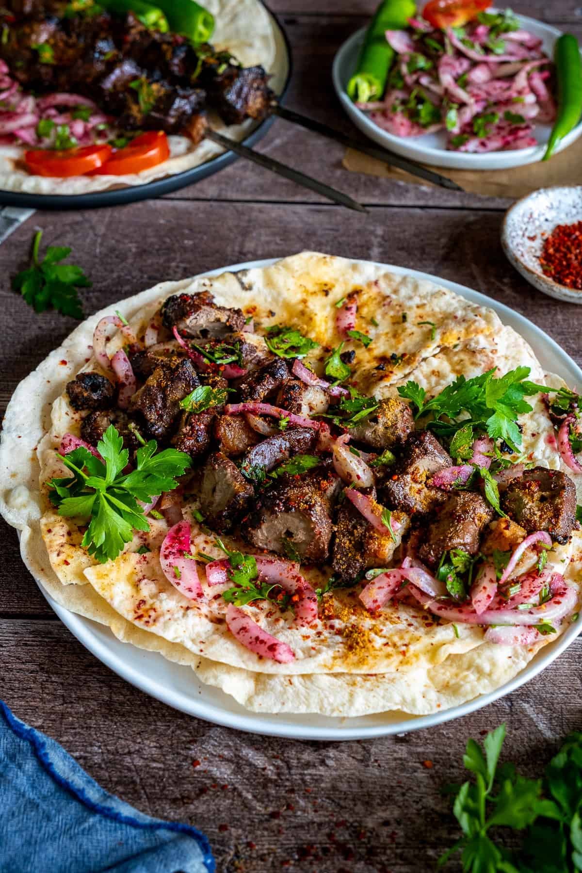 Chunks of grilled Turkish liver kebab served on lavash bread with sumac onion salad and fresh parsley.