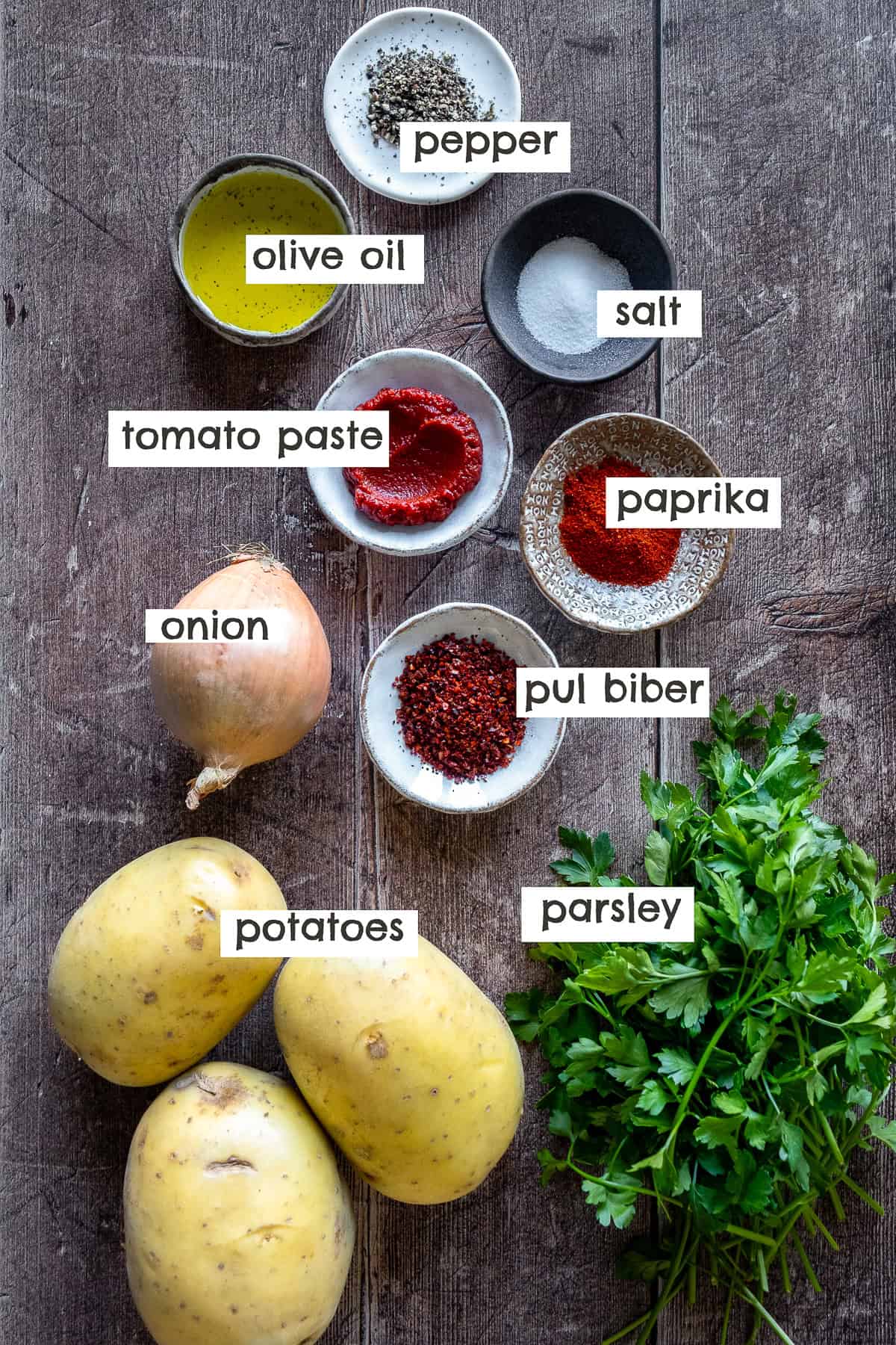 Ingredients for Patates Kavurma: potatoes, onion, tomato paste, olive oil, parsley, paprika, pul biber, salt, and pepper.